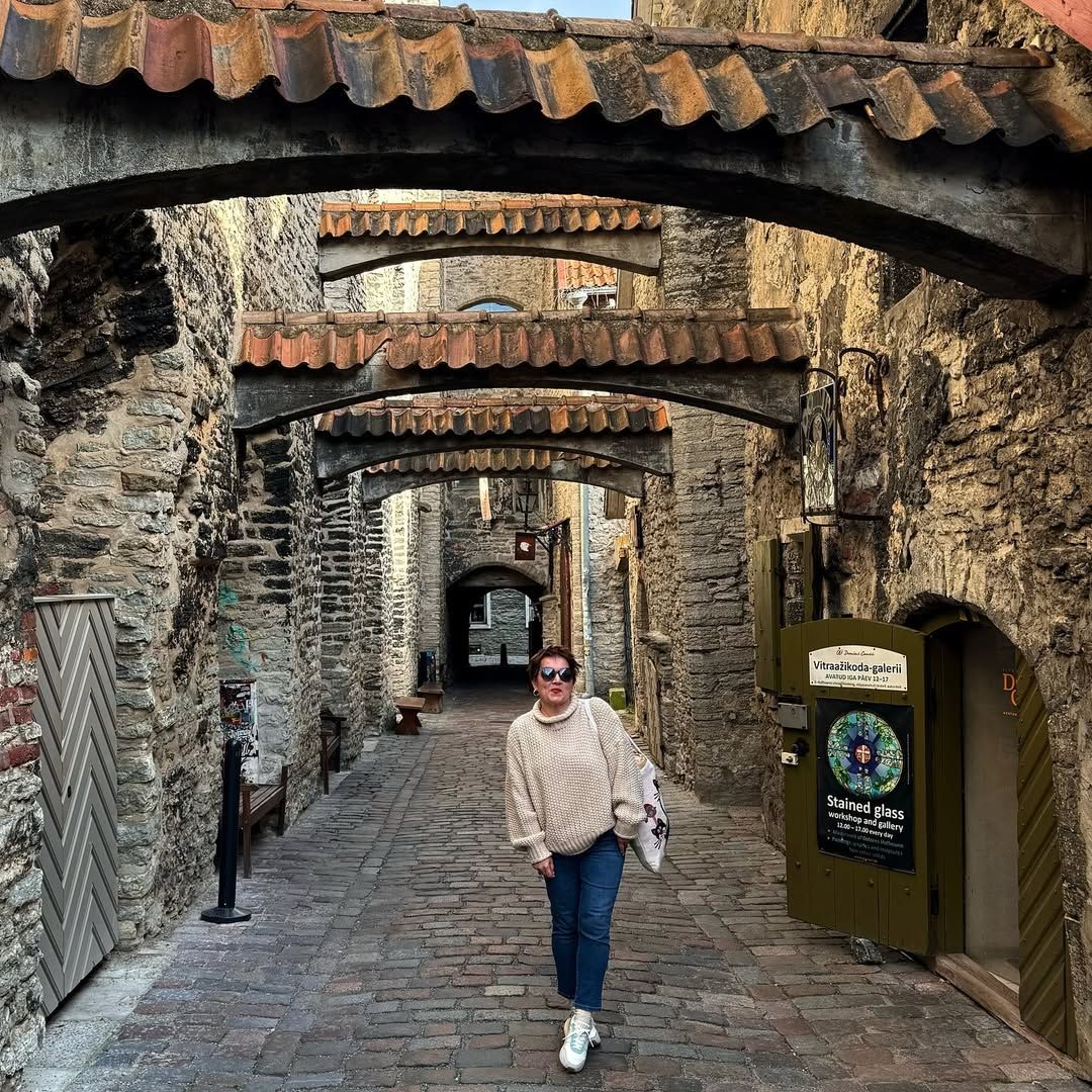 Woman walking through medieval stone archway passage with cobblestones in Tallinn, Estonia
