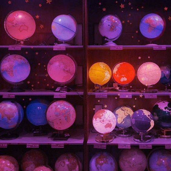 Shelves filled with illuminated world globes in pink, purple, and orange lighting