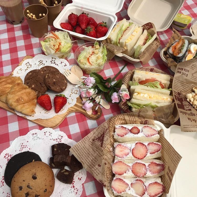 Picnic spread with strawberry desserts, cakes, cookies on red checkered tablecloth