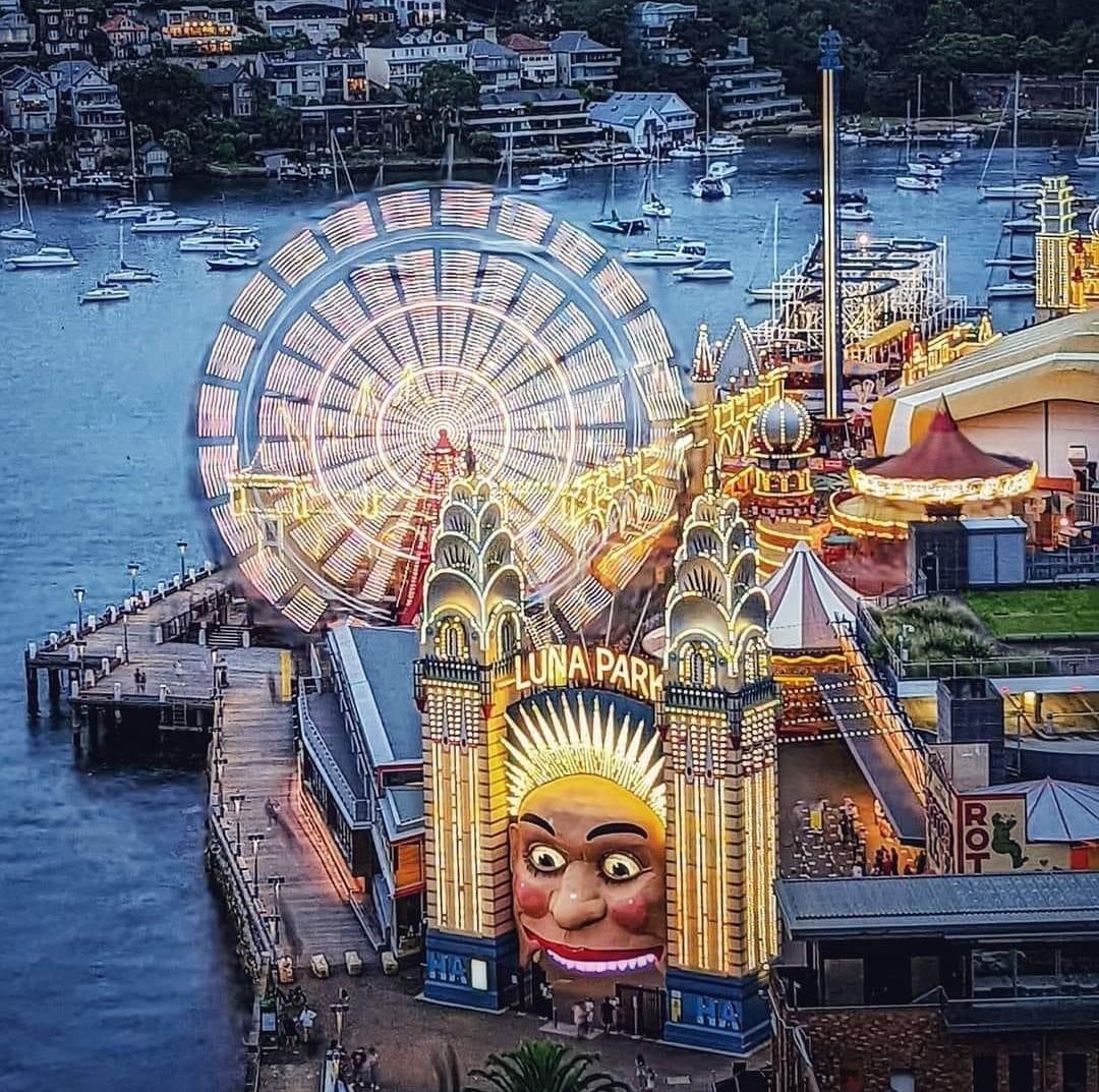 Luna Park amusement park with lit ferris wheel and rides on Sydney Harbour waterfront at twilight
