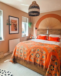 Bedroom with terracotta walls, wicker headboard, orange bedding, and woven pendant light