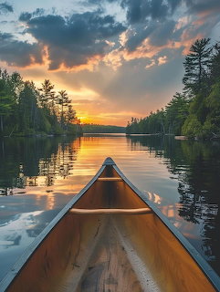 Bow of a wooden canoe on a calm lake at sunset with pine trees and dramatic golden sky