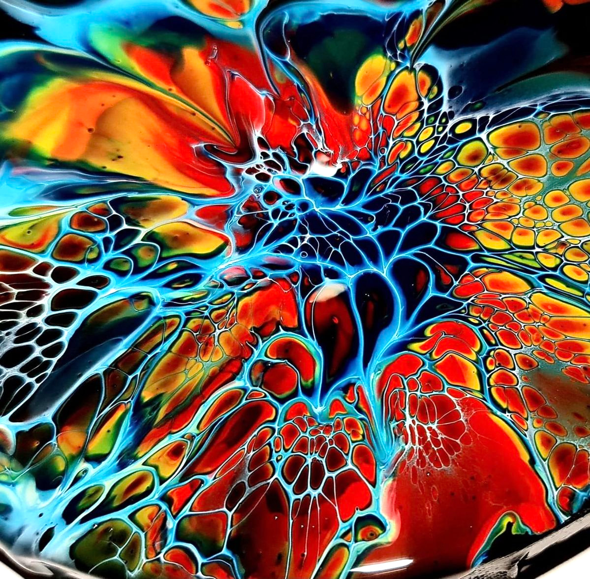 Abstract fluid art with explosive radial patterns in vibrant red, orange, blue, and yellow colors
