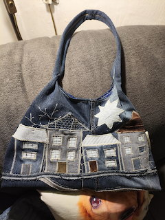 Blue denim handbag with decorative house patches and white star embellishments on handles