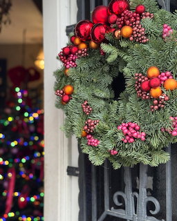 Evergreen Christmas wreath with red berries and ornaments hanging on a door