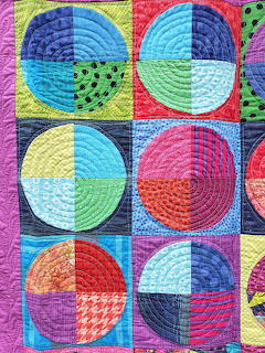Colorful quilted patchwork art with circular geometric patterns in bright squares