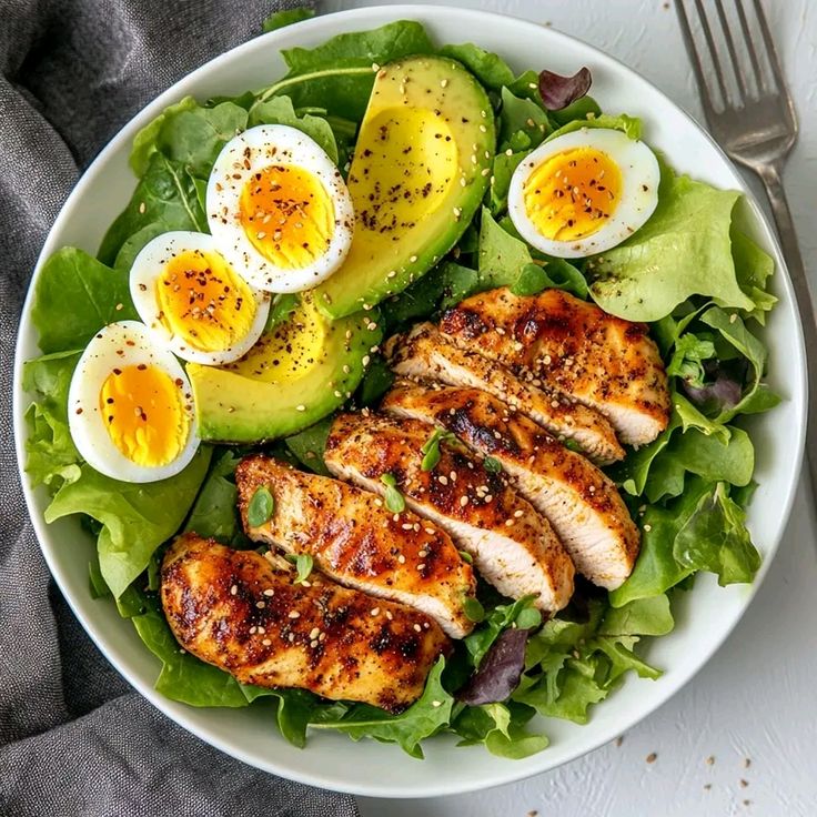 Salad bowl with grilled chicken, avocado slices, boiled eggs, and lettuce