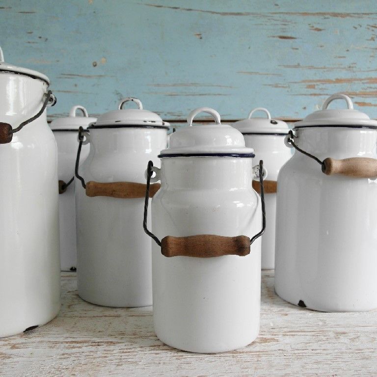 White enamel kettles with wooden handles on a rustic table against a blue wooden wall