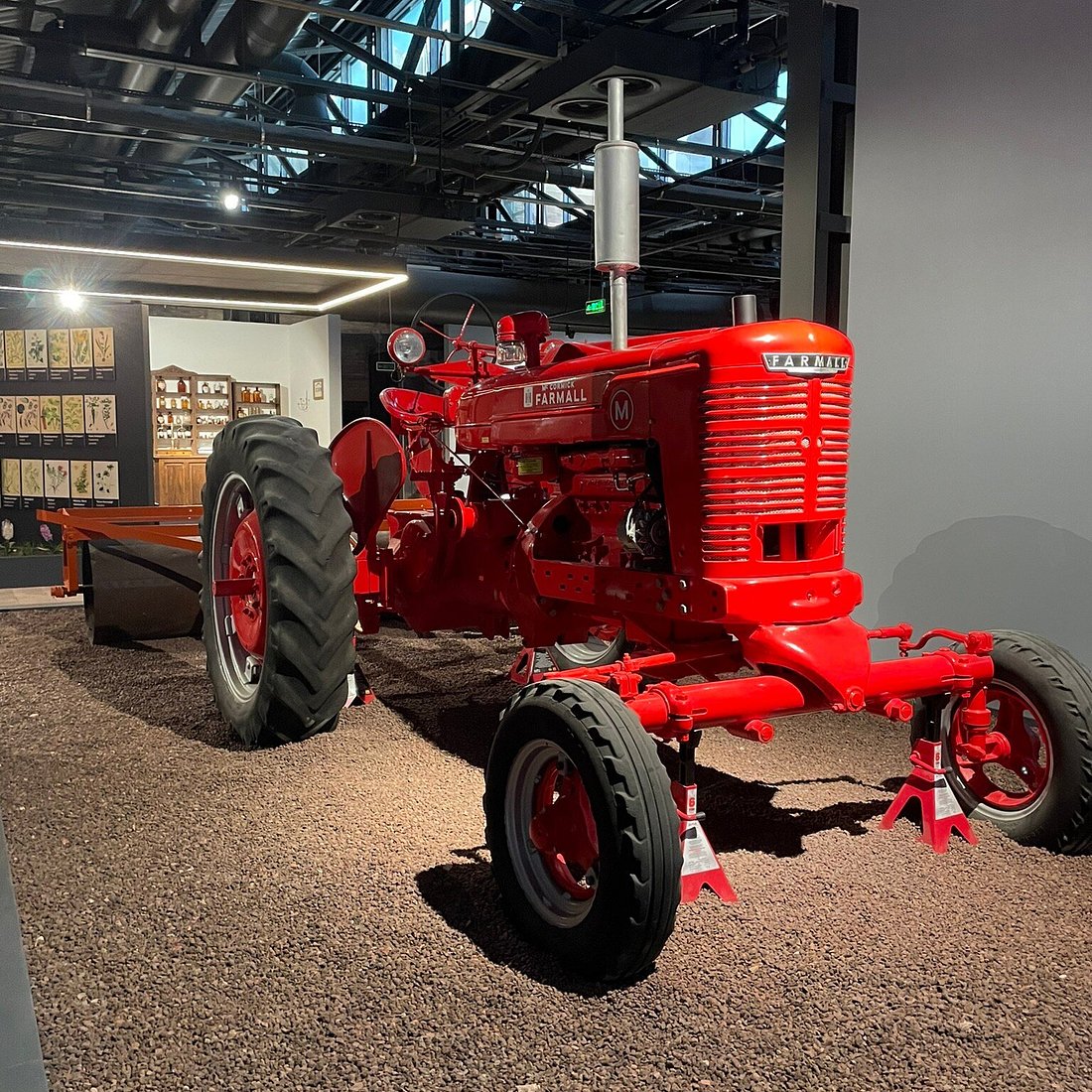 Bright red vintage tractor displayed indoors in museum setting
