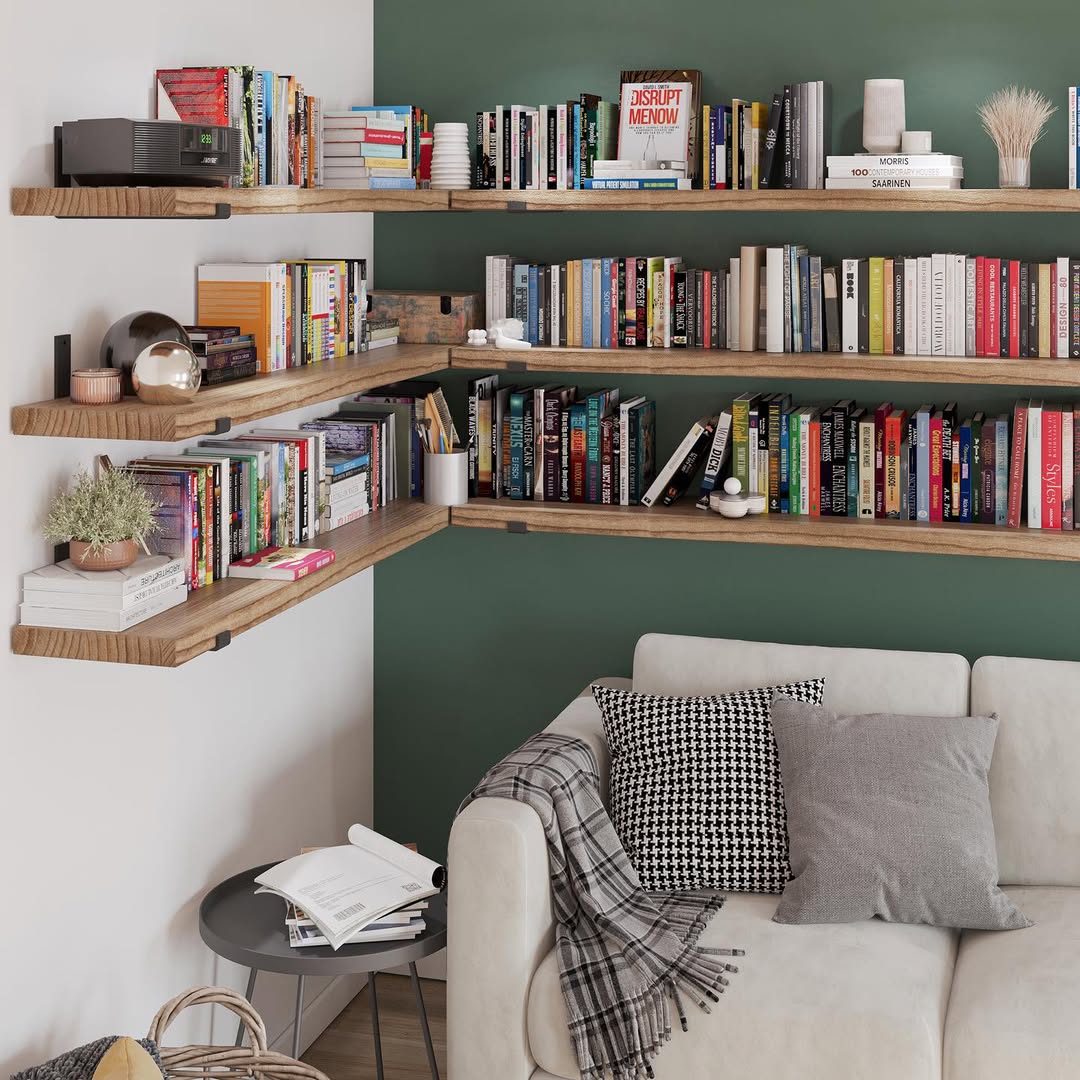 Wooden corner shelves with books above a beige sofa with gray pillows and checkered throw blanket