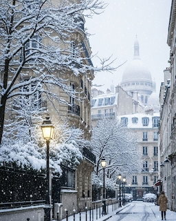 Snowy Paris street with bare trees, glowing streetlamp, and historic buildings on a winter day