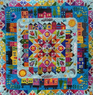 Colorful patchwork quilt with houses, hearts, flowers and geometric patterns in vibrant fabrics