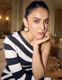 Woman posing indoors in a black and white striped one-shoulder dress