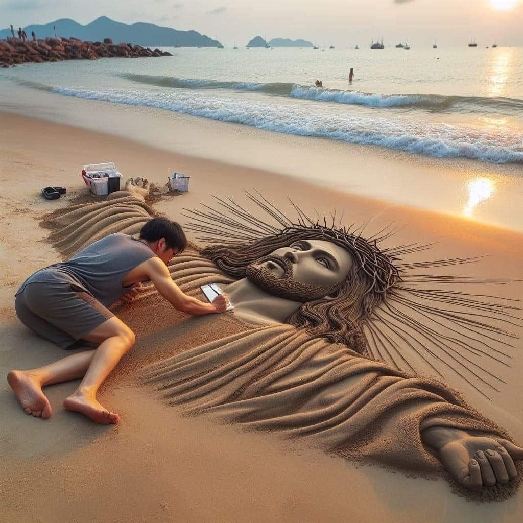 Man sculpting a large sand portrait of Jesus on a beach at sunset