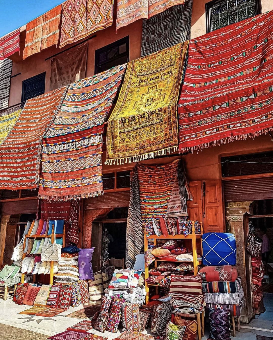 Colorful Morocan rugs and carpets hanging and stacked at an outdoor market stall in Marakech