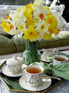 White and yellow daffodils in vase with two cups of tea on tray