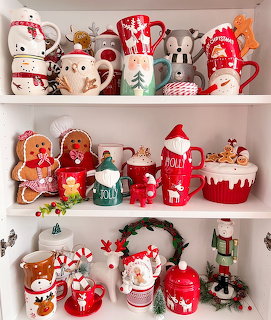 White shelves filled with decorative Christmas mugs and cookie jars in red, green, and white holiday designs