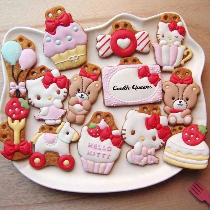 Decorated Hello Kitty and bear cookies arranged on a white plate with cupcake and candy designs