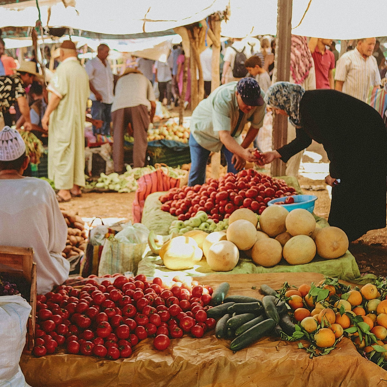 Outdoor market in Marrakesh with vendors and tables of fresh vegetables and fruit