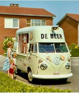 Vintage light blue Volkswagen ice cream van with De Beer sign parked near houses with woman and child