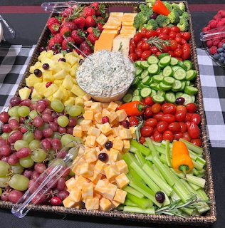 Overhead view of vibrant fruit and vegetable platter with dip center arranged on checkered table