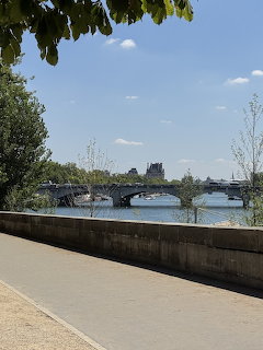 Walkway along the Seine river in Paris with a bridge and city buildings in the background