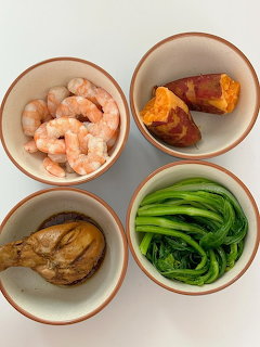 Four ceramic bowls with shrimp, sweet potato, braised chicken, and green vegetables on a beige surface