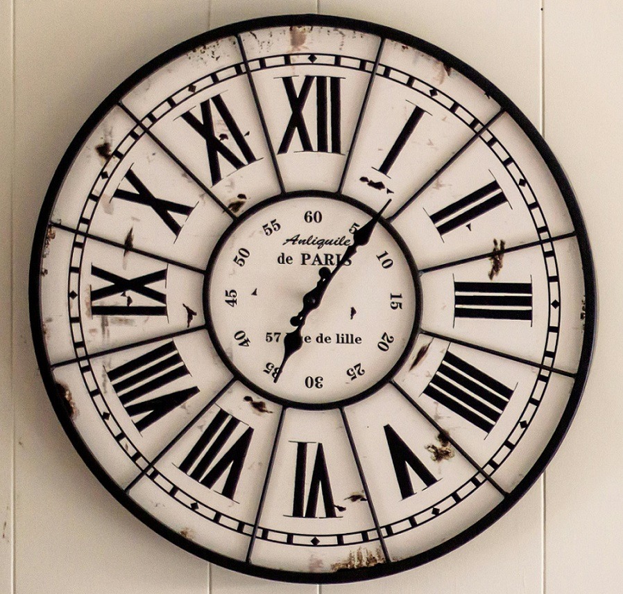Vintage wall clock with Roman numerals and decorative black hands on cream face