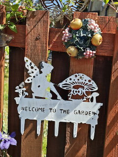 White metal deer and mushroom cutout on wooden fence with welcome sign and floral wreath