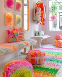 Colorful boho living room with rainbow striped poufs, neon art, and vibrant textiles