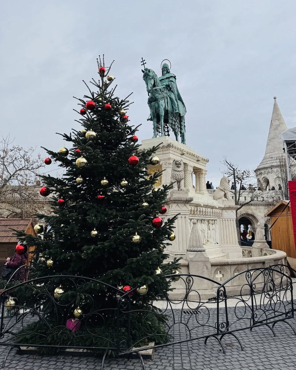 Decorated Christmas tree next to bronze statue in Budapest Castle District with white stone architecture