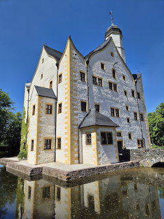 White Renaissance castle with turrets and moat reflection under blue sky