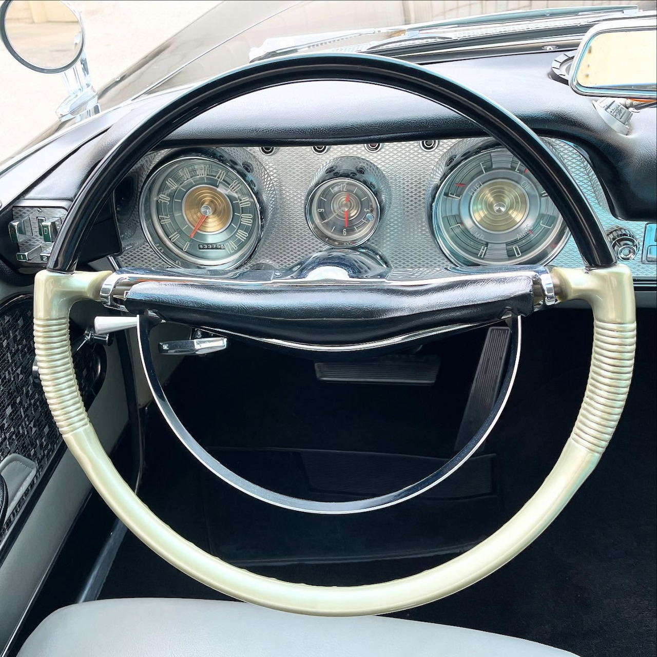 Close-up of 1959 Chrysler New Yorker dashboard with chrome gauges and two-tone steering wheel