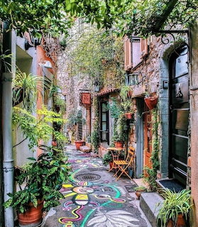Narrow cobblestone alley in Mougins with colorful mosaic floor, greenery, and Mediterranean architecture