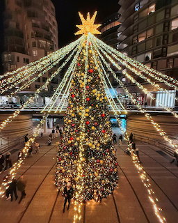 Large decorated Christmas tree with glowing star and radiating light trails outdoors at night