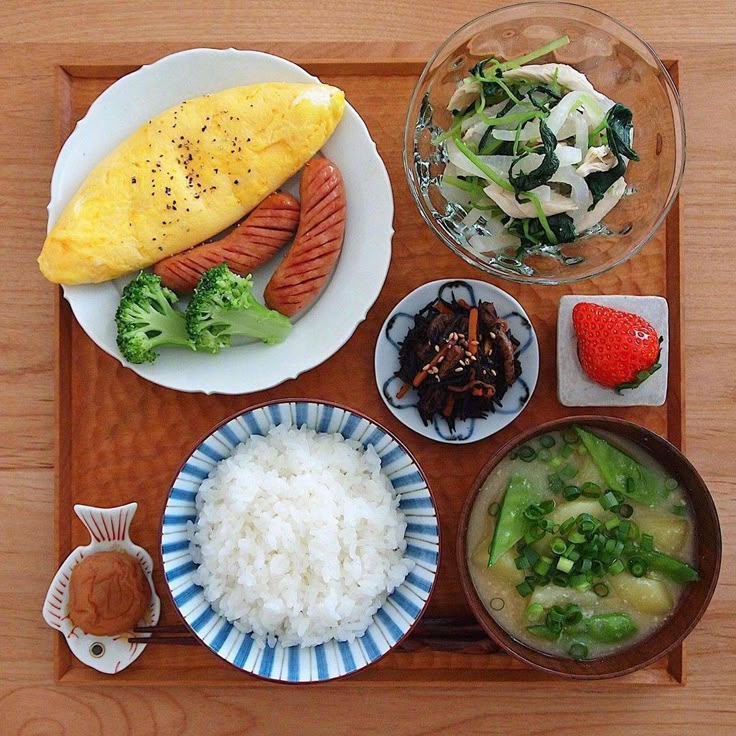 Overhead view of Korean meal with rice, omelette, kimchi, soup and vegetables on wooden table