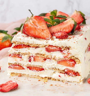 Layered strawberry icebox cake with whipped cream, graham crackers, and fresh strawberries on marble surface
