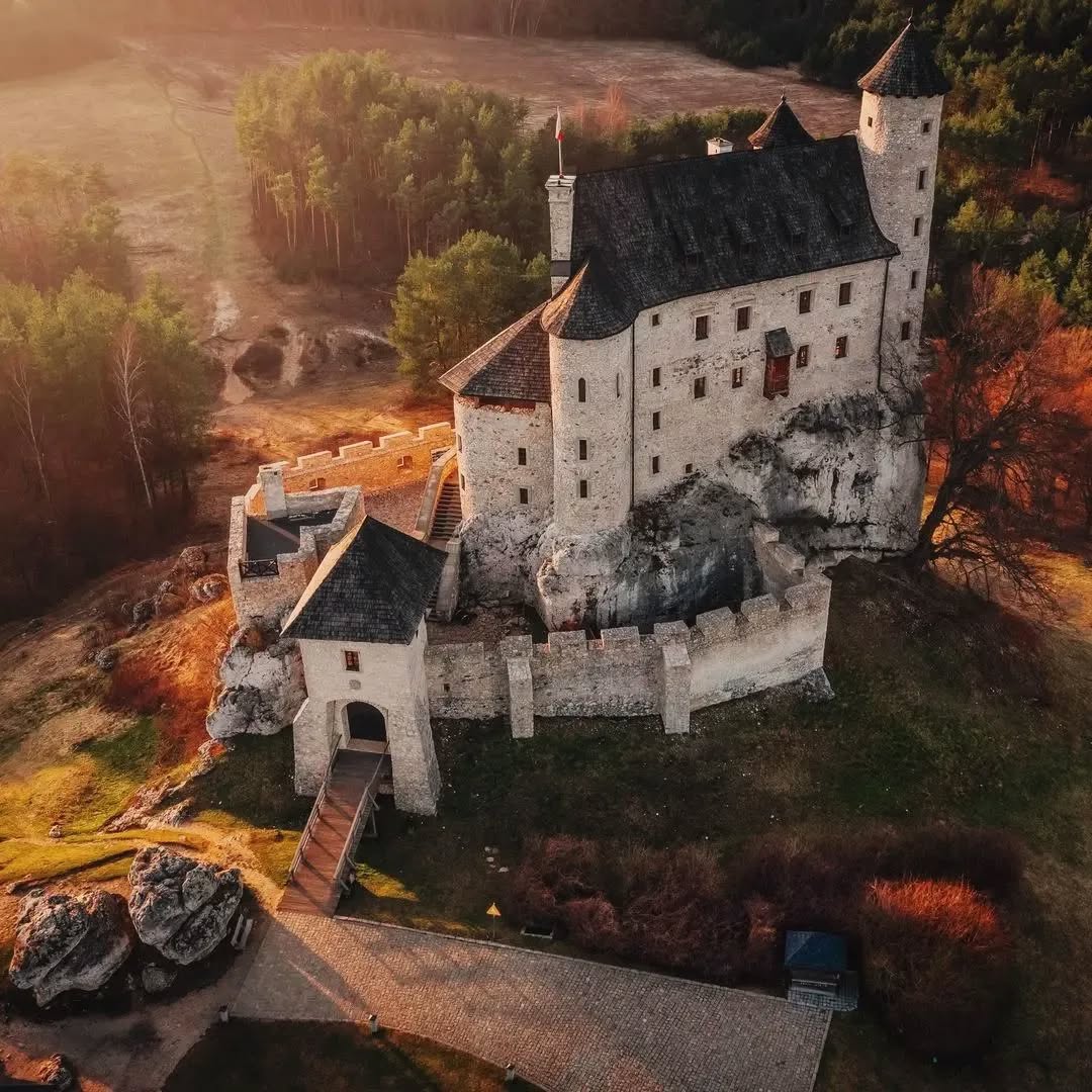 Aerial photo of Bobolice Castle in Poland with stone walls and towers surrounded by autumn foliage