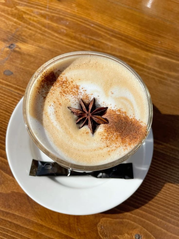 Chai latte with foam, cinnamon dusting, and star anise on white saucer
