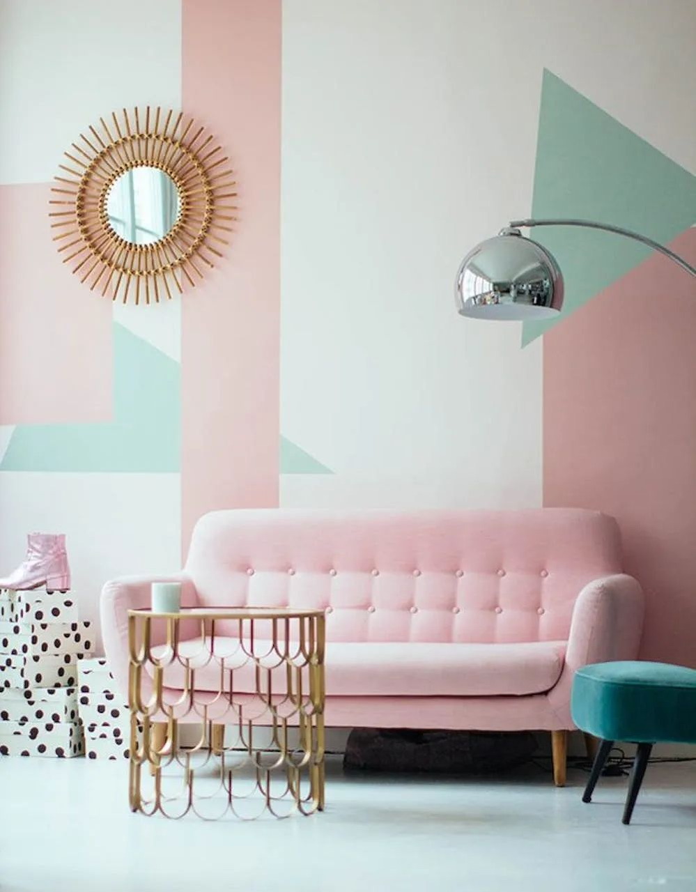 Pastel living room with pink sofa, sunburst mirror, gold table, and chrome arc lamp
