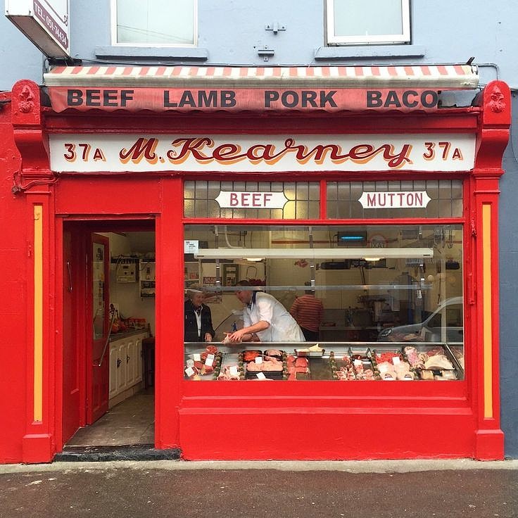 Red painted butcher shop storefront with M. Kearney sign and meat display window