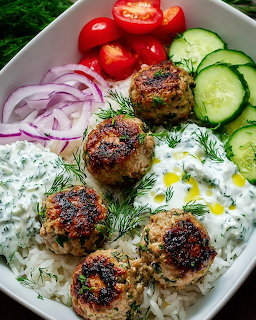 White bowl with kofte meatballs, rice, tzatziki, cucumbers, tomatoes, red onion, and dill garnish