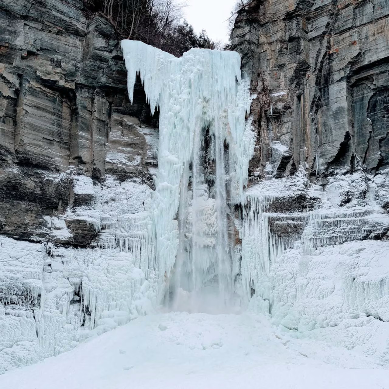 Frozen waterfall between rocky cliffs with snow and thick ice