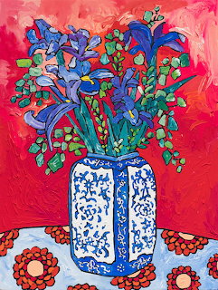Colorful painting of blue iris flowers in an ornate vase on red background