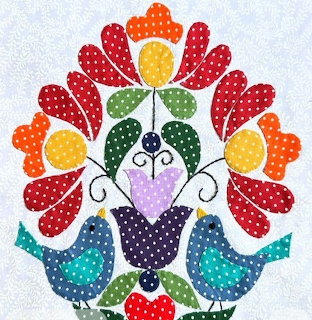 Folk art appliqué with two blue birds and a vibrant floral bouquet in red, orange, yellow, and green