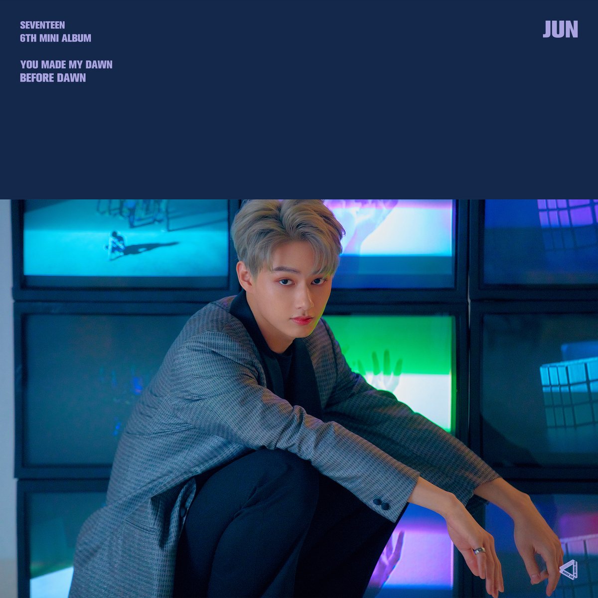 Young man crouching in front of colorful glowing TV screens