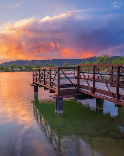 Wooden pier over a calm lake at sunset with colorful clouds and mountain backdrop in Salida, Colorado