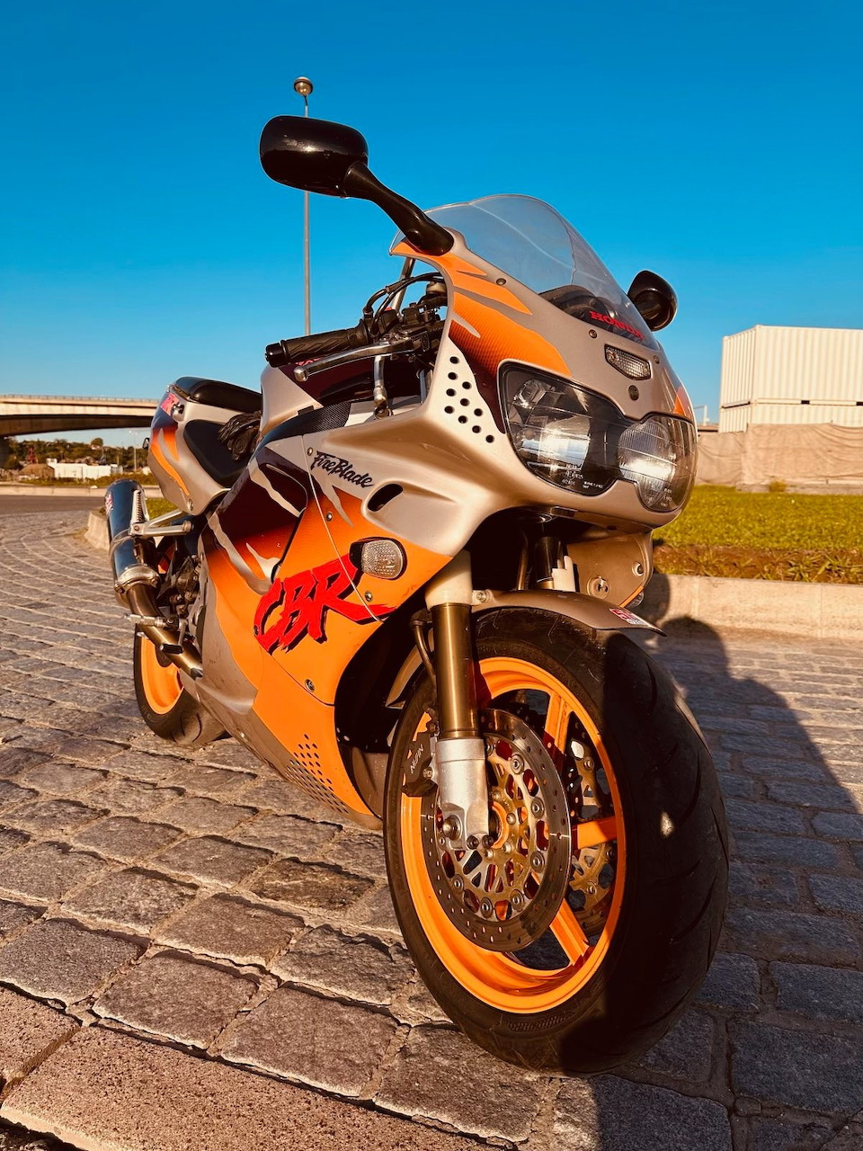 Orange Honda CBR sport motorcycle parked on paving, viewed from the front side