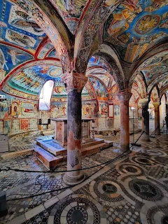 Ornate cathedral interior with frescoed arches, stone columns, and patterned mosaic floor