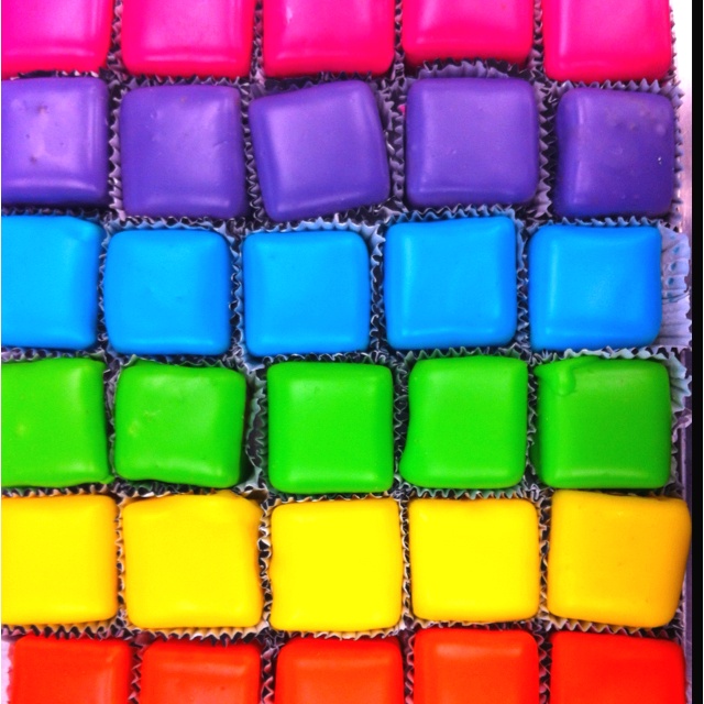 Grid of colorful square glass tiles arranged in rainbow spectrum rows with dark grout
